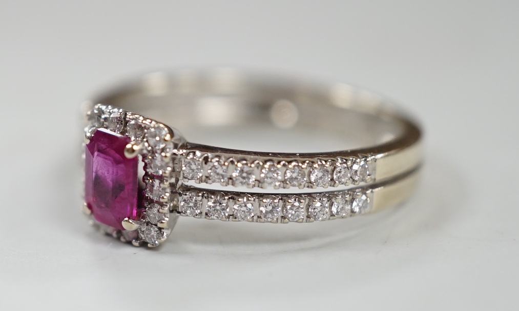 A modern 18ct white gold, single stone emerald cut ruby and diamond chip set cluster ring, with two row diamond chip set shoulders, size K, gross weight 3.3 grams.